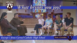 Group of high-school students seated in a church chapel, listening to two friars, with a blue banner reading 'What brings you joy?' and a Carmel crest logo on the left.